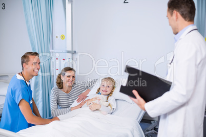 Doctor talking to girl patient in hospital bed