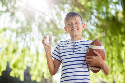 Boy holding asthma inhaler and a rugby ball