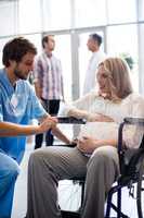 Male doctor talking to pregnant woman in wheelchair