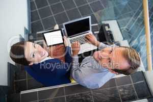 Businessman and woman sitting on steps holding laptop and digital tablet