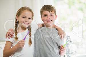 Siblings brushing teeth in bathroom