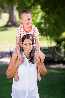 Portrait of mother carrying son on her shoulder in park