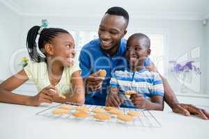 Smiling father and kids eating cookies at home