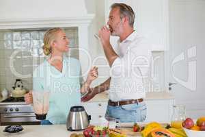 Smiling couple having juice in kitchen at home