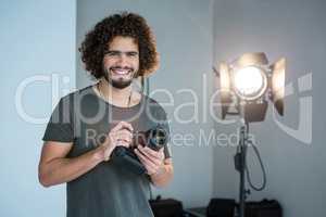 Happy photographer holding a camera in the studio