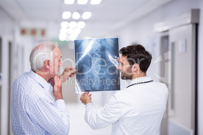 Doctor discussing x-ray with patient in corridor