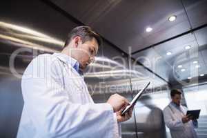 Doctor using digital tablet in corridor