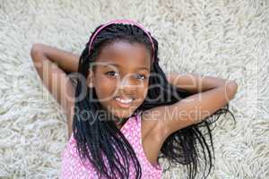 Portrait of girl lying on rug in living room