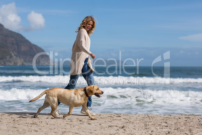 Woman walking with her dog on the beac