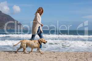 Woman walking with her dog on the beac