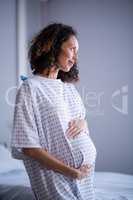 Thoughtful pregnant woman standing in ward