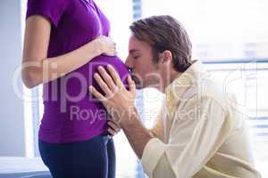 Man kissing pregnant womans belly in ward