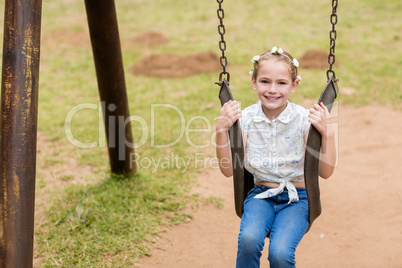 Happy girl sitting on a swing in park