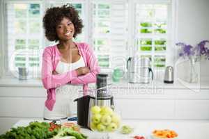Smiling woman standing with arms crossed in kitchen
