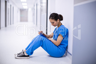 Female doctor reading reports in corridor