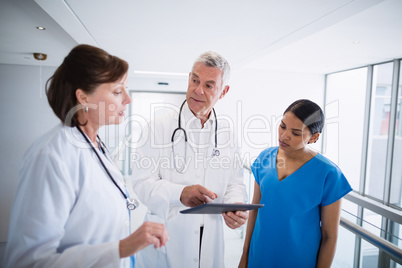 Nurse and doctors discussing over digital tablet