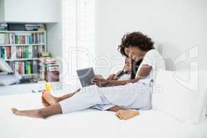 Mother and daughter using digital tablet in bedroom