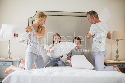 Cute family having a pillow fight in bedroom