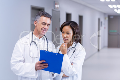 Doctors having discussion on clipboard in corridor