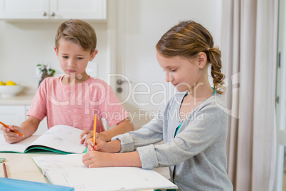 Siblings doing homework in living room