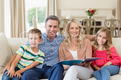 Portrait of parents and kids sitting together on sofa with photo album