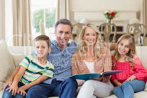 Portrait of parents and kids sitting together on sofa with photo album