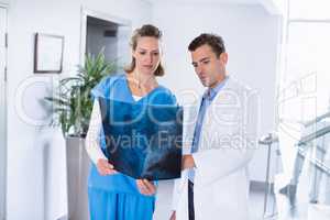 Two doctors looking over patients x-ray in corridor