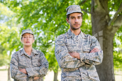 Portrait of a military couple standing with arms crossed in park