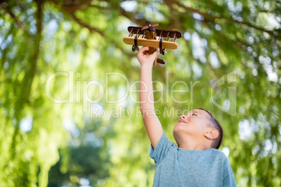 Boy playing with a wooden toy aeroplane in park