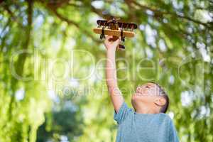 Boy playing with a wooden toy aeroplane in park