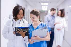 Doctors having discussion on clipboard in corridor