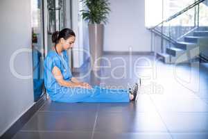 Tensed female doctor sitting in corridor