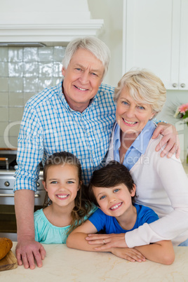 Portrait of grandparents and grandchildren standing at kitchen