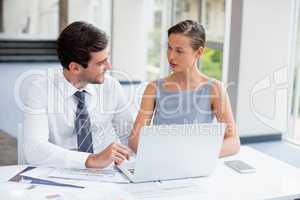 Business executives discussing over laptop