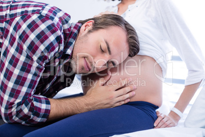 Man listening to pregnant womans belly in ward