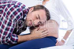 Man listening to pregnant womans belly in ward