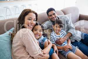 Portrait of happy parents and kids sitting on sofa in living room