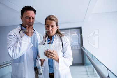 Male and female doctor discussing over digital tablet