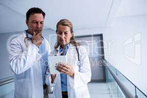 Male and female doctor discussing over digital tablet