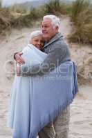 Senior couple wrapped in shawl on the beach