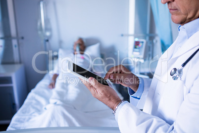 Mid-section of male doctor using digital tablet