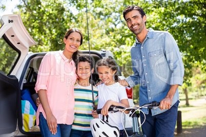 Happy family on a picnic standing next to their car