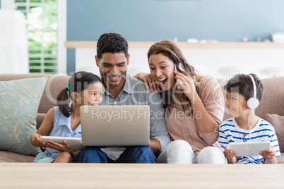 Parents and kids using laptop and digital tablet in living room