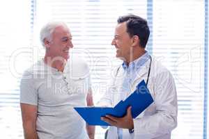 Doctor and senior man smiling while having discussion on file