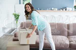 Portrait of woman holding cardboard boxes in living room