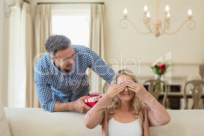 Man giving surprise gift to woman in living room