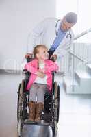 Doctor pushing girl in wheelchair