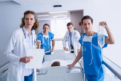 Doctors pushing emergency stretcher bed in corridor