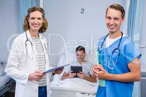 Doctors standing with reports and patient using digital tablet in background