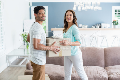 Couple holding card boxes in living room at home